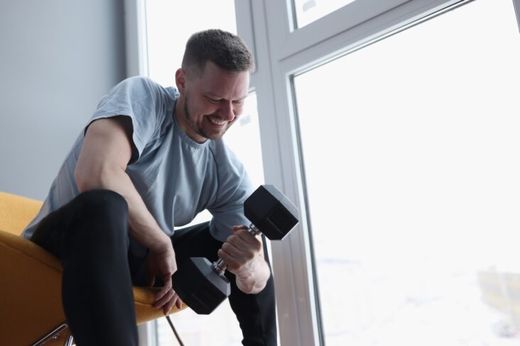 Man does exercises with dumbbells for biceps. Home strength training concept