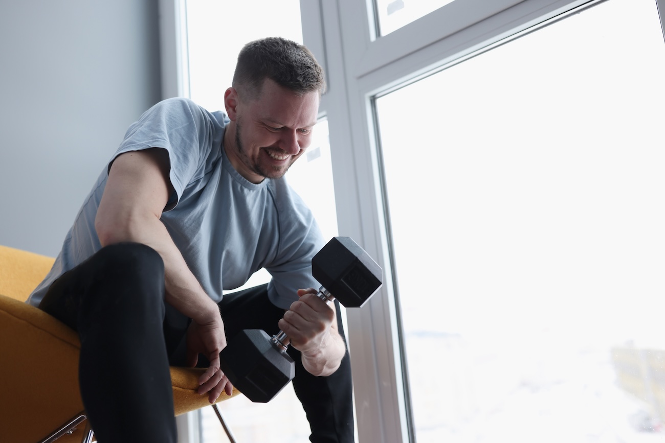 Man does exercises with dumbbells for biceps. Home strength training concept